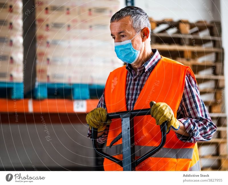 Konzentrierter erwachsener Arbeiter, der einen Rollwagen benutzt und im Lager arbeitet Mann Lagerhalle Handwagen Karre Mitarbeiter Fokus Konzentration