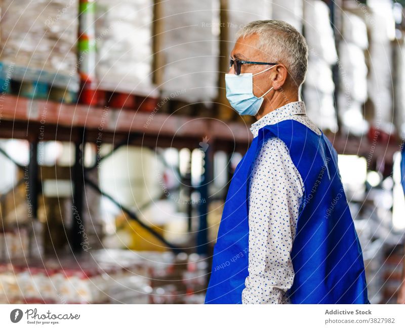 Ruhiger männlicher Arbeiter im Lagerhaus stehend Mann professionell Lagerhalle bei der Arbeit Industrie Uniform Windstille Fokus Speicher industriell