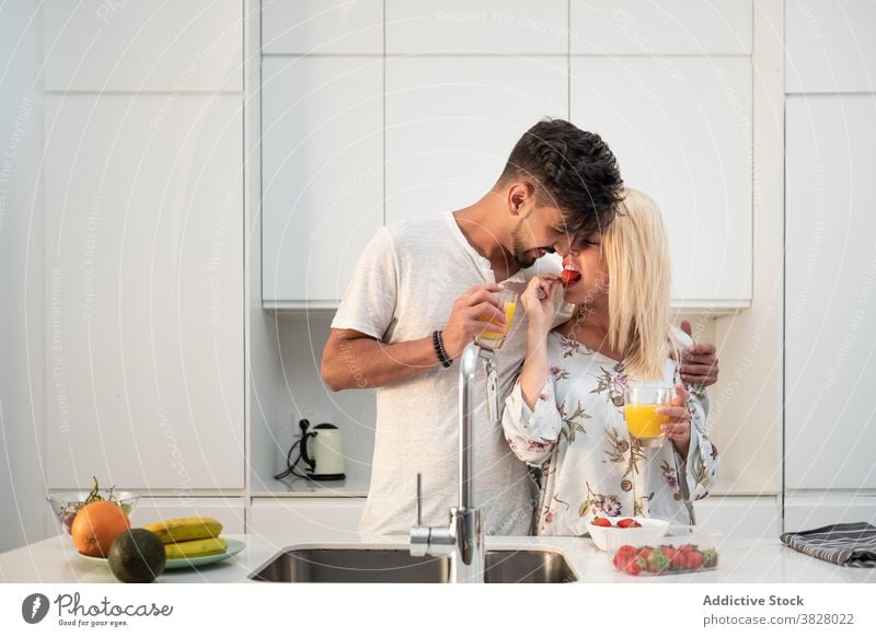 Verliebtes Paar beim Frühstück in moderner Küche Zusammensein Erdbeeren essen genießen Morgen Umarmung Liebe früh frisch orange Saft Lebensmittel Frucht