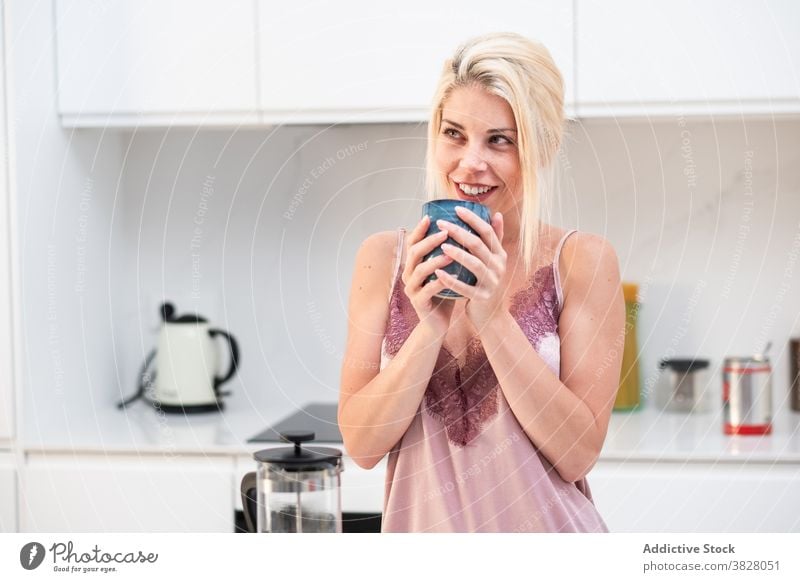 Frau trinkt Kaffee nach dem Aufwachen zu Hause Morgen Frühstück Energie Koffein Küche genießen trinken frisch modern Tisch Pyjama Seide Windstille Appartement