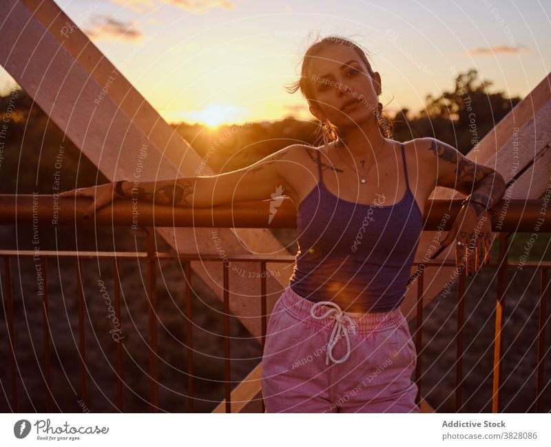 Stilvolle Frau in Tattoos stehen in der Stadt trendy Brücke Metall Sonnenuntergang Sommer sich[Akk] entspannen ruhen genießen jung urban Freiheit Freude froh