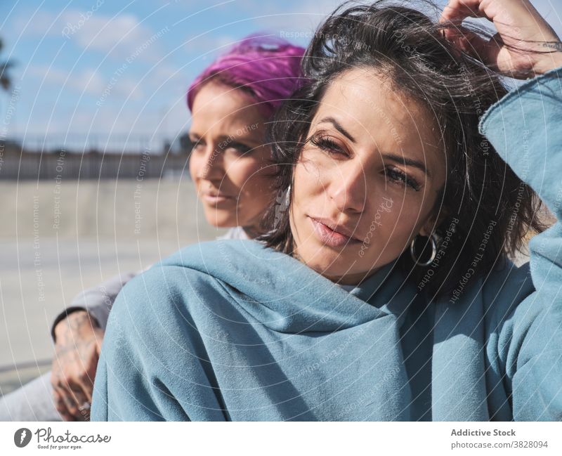 Stilvolle Frauen im Skatepark im Sommer rosa Haare informell Freund tausendjährig Hipster Zusammensein Tattoo Vorschein urban Straße exzentrisch Freundschaft