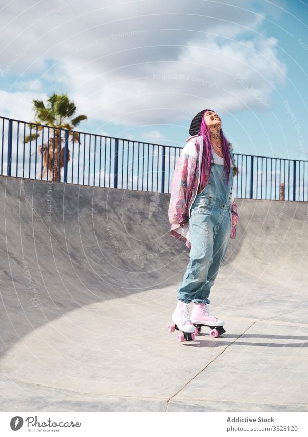 Stilvolle Frau mit rosa Haaren in Rollschuhen Rolle Skateplatz Schlittschuh Hipster Streetstyle informell exzentrisch Vorschein Hobby Spaß haben Outfit Straße