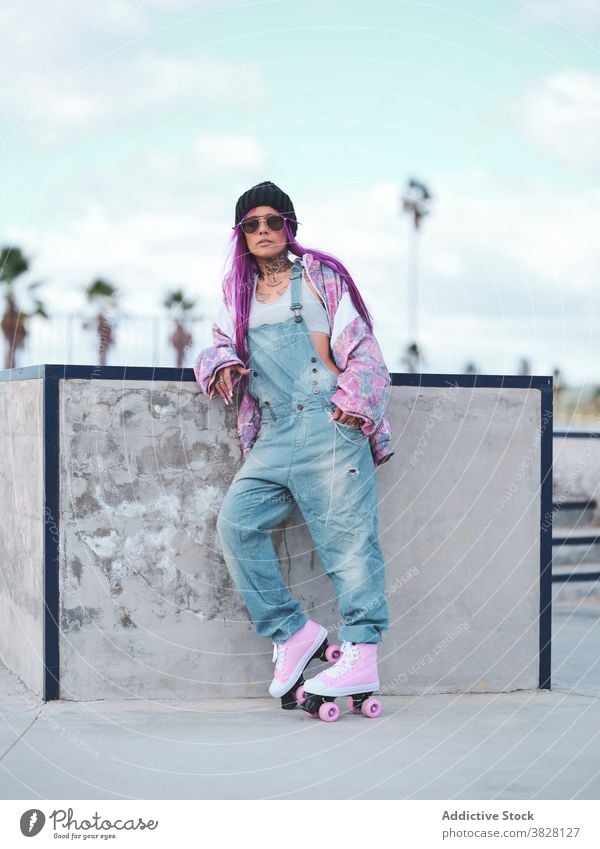 Stilvolle Frau mit rosa Haaren in Rollschuhen Rolle Skateplatz Schlittschuh Hipster Streetstyle informell exzentrisch Vorschein Hobby Spaß haben Outfit Straße