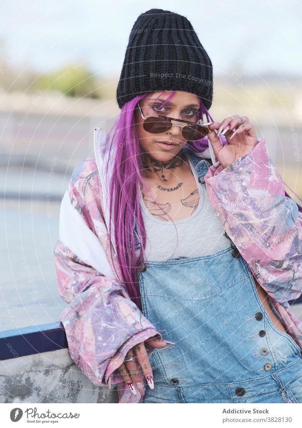 Frau im Hip-Hop-Outfit in der Stadt tausendjährig trendy ausgefallen Stil Sonnenbrille Tattoo Streetstyle Stilrichtung rosa Haare Großstadt cool jung urban