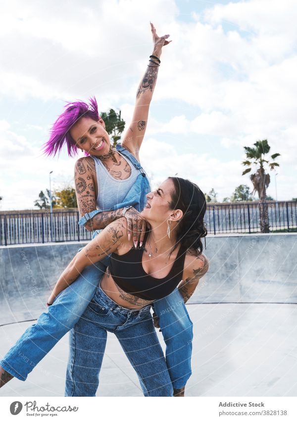 Fröhliche Frauen haben Spaß zusammen im Skatepark Huckepack Spaß haben Freund Freundschaft informell Tattoo Zusammensein Subkultur cool Freude Lachen Optimist