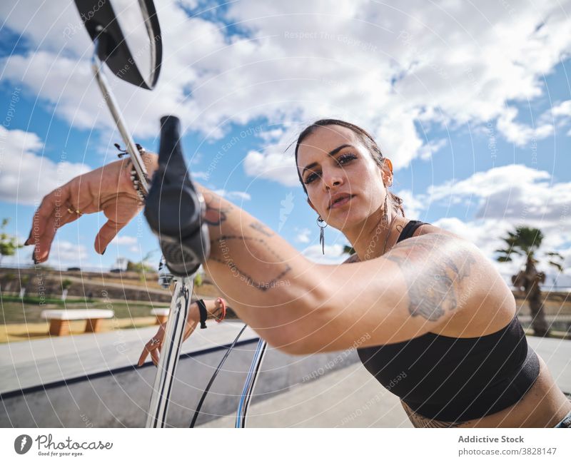 Ernste Frau auf dem Fahrrad im Skatepark bmx selbstbewusst Skateplatz extrem ernst Tattoo Stil Outfit sitzen trendy urban jung cool Verkehr Freiheit Sommer