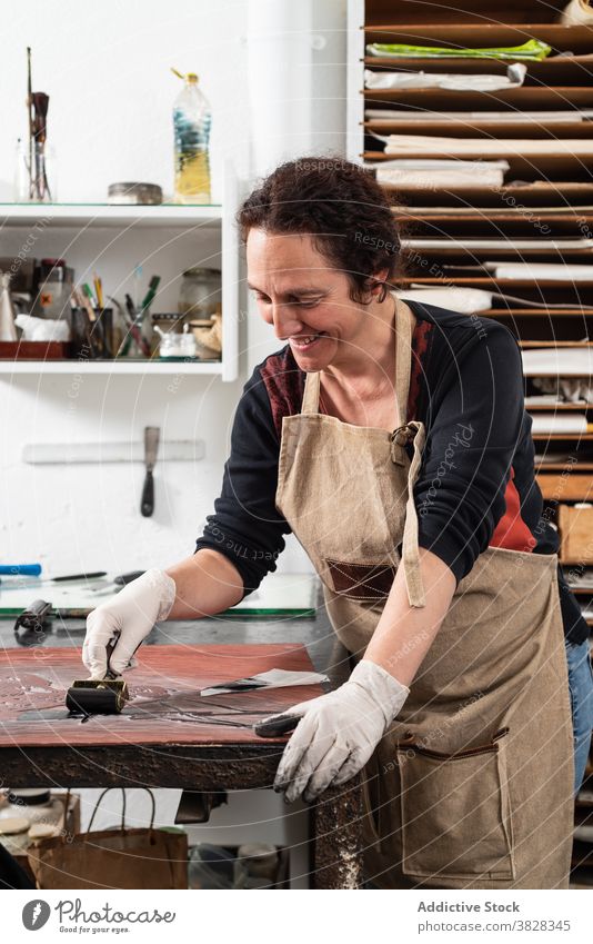 Handwerkerin bei der Herstellung eines Drucks in der Gravurwerkstatt gravieren Druckgrafik Tusche drucken kreieren Kunstgewerbler professionell Kunstwerk