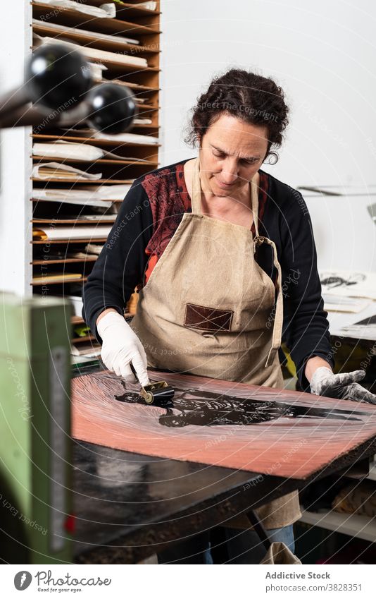 Handwerkerin bei der Herstellung eines Drucks in der Gravurwerkstatt gravieren Druckgrafik Tusche drucken kreieren Kunstgewerbler professionell Kunstwerk