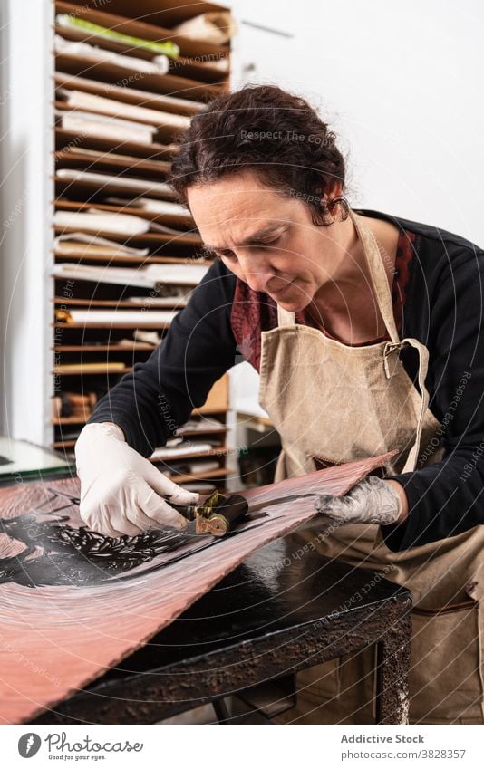 Handwerkerin bei der Herstellung eines Drucks in der Gravurwerkstatt gravieren Druckgrafik Tusche drucken kreieren Kunstgewerbler professionell Kunstwerk