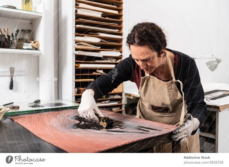 Handwerkerin bei der Herstellung eines Drucks in der Gravurwerkstatt gravieren Druckgrafik Tusche drucken kreieren Kunstgewerbler professionell Kunstwerk