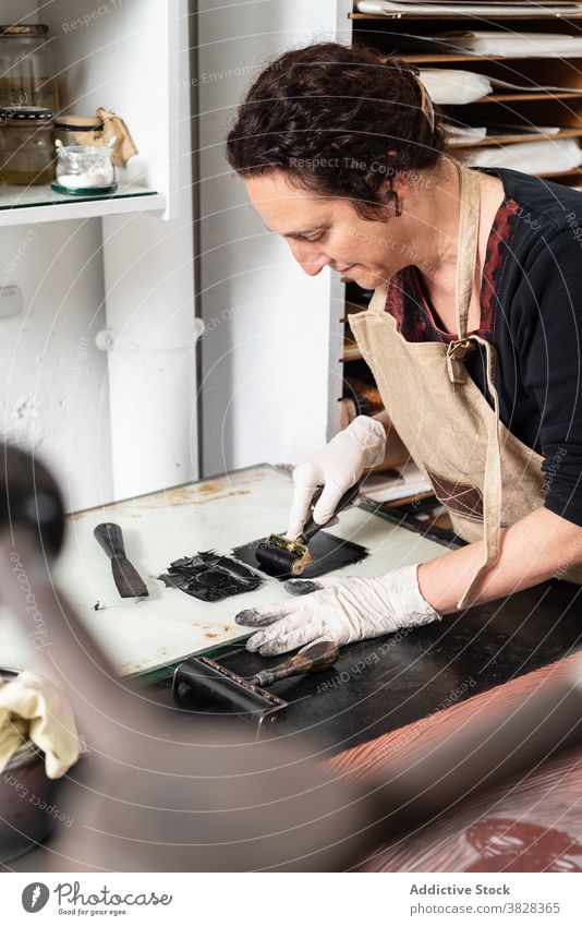 Künstlerin mit Walze beim Auftragen von Farbe auf eine Platte für eine Gravur gravieren Druckgrafik Rolle Tusche drucken kreieren Handwerk Kunstgewerbler