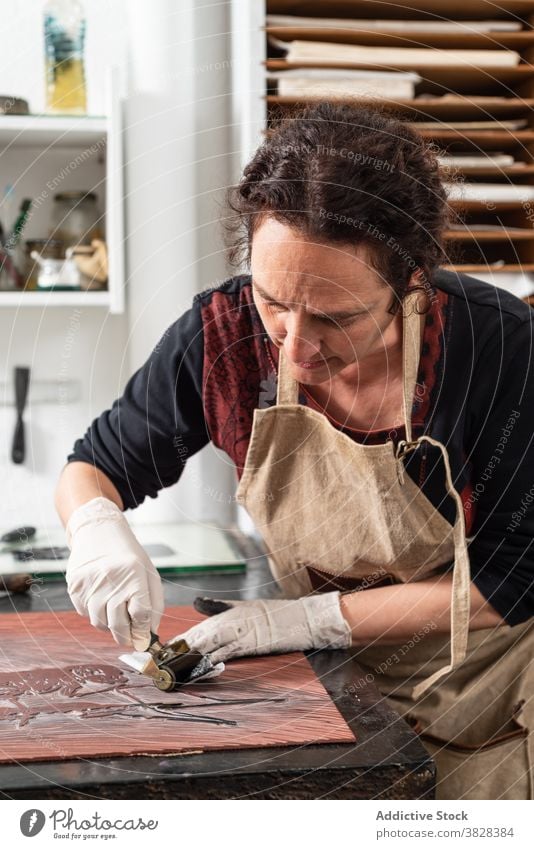 Handwerkerin bei der Herstellung eines Drucks in der Gravurwerkstatt gravieren Druckgrafik Tusche drucken kreieren Kunstgewerbler professionell Kunstwerk