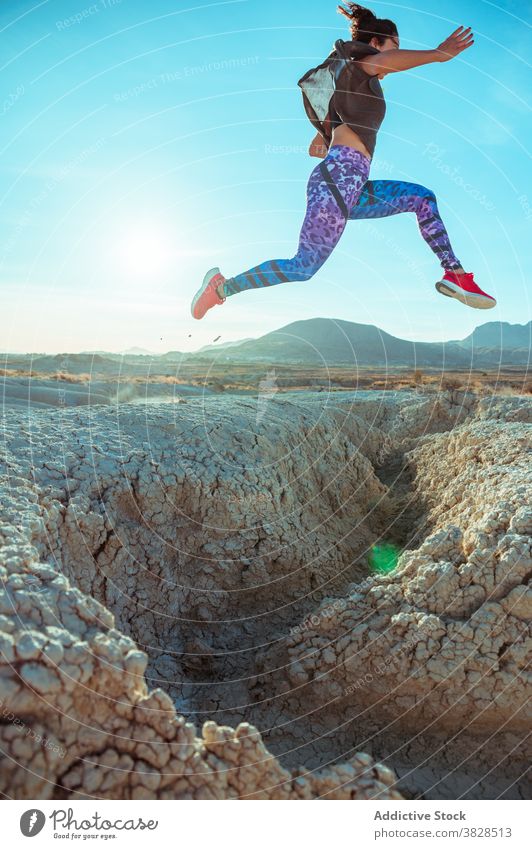 Starke Sportlerin springt über sandigen Hügel springen Fliege Skyline Blauer Himmel wüst rau aktiv Energie Sprung Athlet Frau Berghang Gelände Natur Training