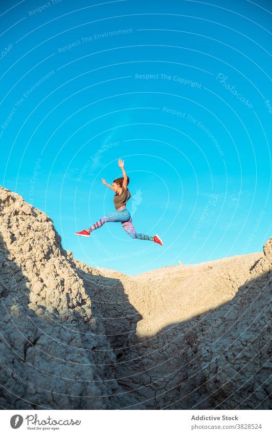 Starke Sportlerin springt über sandigen Hügel springen Fliege Skyline Blauer Himmel wüst rau aktiv Energie Sprung Athlet Frau Berghang Gelände Natur Training