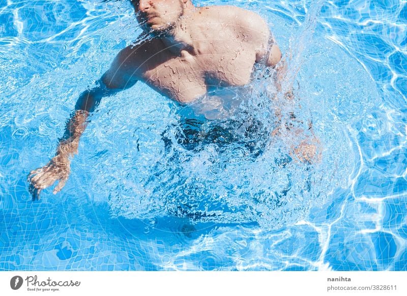 Junger Mann genießt den Tag im Schwimmbad Pool Schwimmsport spielerisch Sommer Wasser attraktiv cool frisch Feiertage Spaß lustig Sport sportlich Badehose