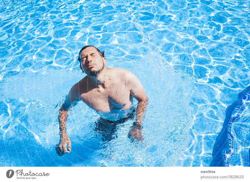 Junger Mann genießt den Tag im Schwimmbad Pool Schwimmsport spielerisch Sommer Wasser attraktiv cool frisch Feiertage Spaß lustig Sport sportlich Badehose