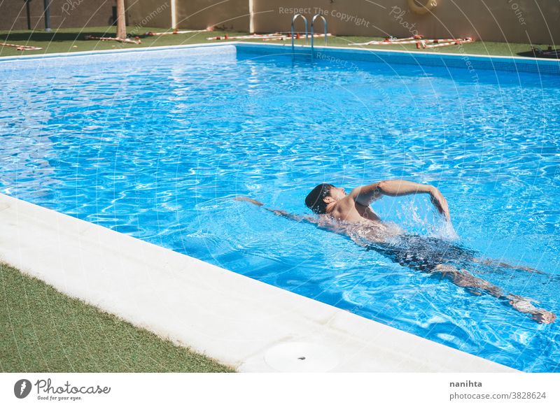 Junger Mann genießt den Tag im Schwimmbad Pool Schwimmsport spielerisch Sommer Wasser attraktiv cool frisch Feiertage Spaß lustig Sport sportlich Badehose