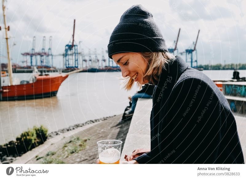 Feierabendbier Frau blond blondes Haar lächelnd lächelnde Frau schön nordisch Wollmütze Wollmantel Hafen Hamburg Hansestadt Hamburger Hafen Elbe Elbstrand