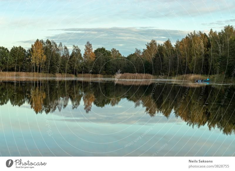 Farbenprächtige Herbstlandschaft. Blauer Himmel. Schöne Wolken. Farbenfroher Herbstabend im See. Herbstlicher Wald, der sich im Wasser spiegelt. Schöne Landschaft mit farbenfrohem Wald.