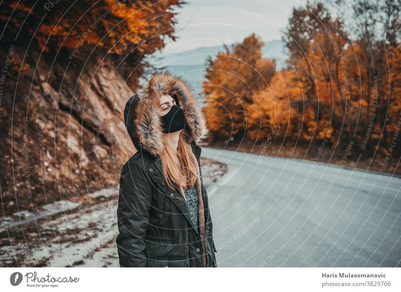 Frau mit Maske und geschlossenen Augen auf Bergstraße stehend Herbst Herbstfarben Herbstlaub Herbst-Vibes Hintergrund schön schöne Frau Kaukasier Feier