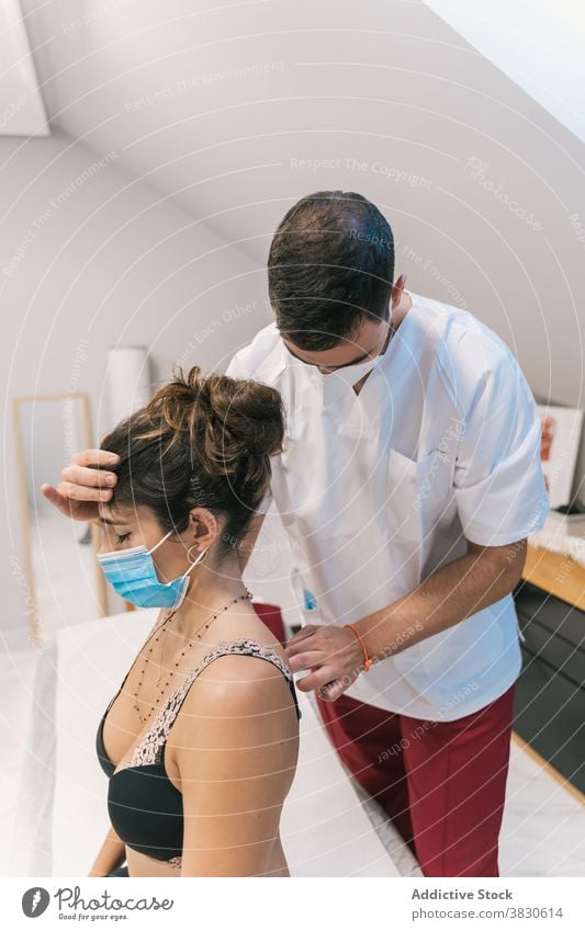 Männliche Therapeut tun Massage für Patienten Therapie Physiotherapie Verfahren Leckerbissen Gesundheitswesen Klinik geduldig Mundschutz medizinisch Tisch