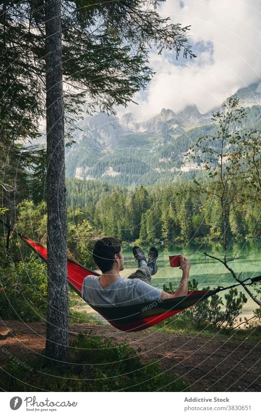 Mann ruht in Hängematte in der Nähe von See umgeben von Bergen Reisender sich[Akk] entspannen Berge u. Gebirge Natur Urlaub genießen männlich Tourismus Fernweh