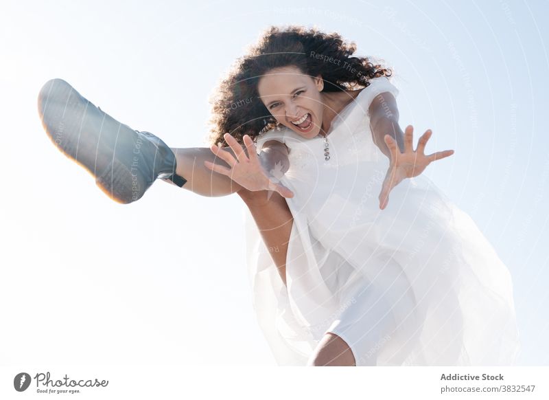 Fröhliche glückliche Frau springt und schreit Schrei auflehnen springen freudig Freiheit cool ethnisch Lachen Dehnung weißes Kleid Sommer schreien positiv jung