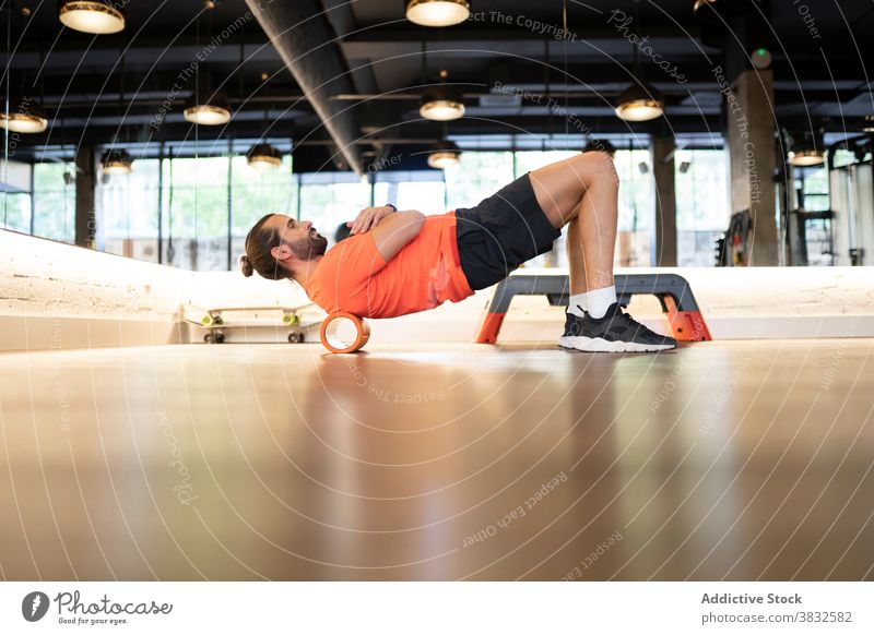 Bärtiger Sportler beim Rückentraining auf der Rolle Übung Fitness Training Fitnessstudio modern passen Gesundheit männlich Athlet stark Wellness Kraft