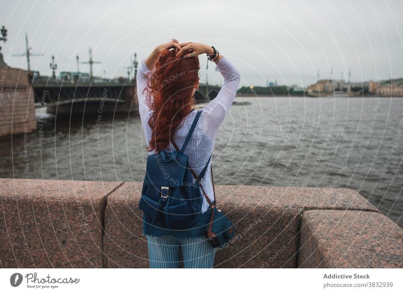 Frau genießt frischen Wind in der Nähe des Flusses in der Stadt urban Freiheit Reisender genießen Brücke Sightseeing rote Haare Rotschopf Tourist