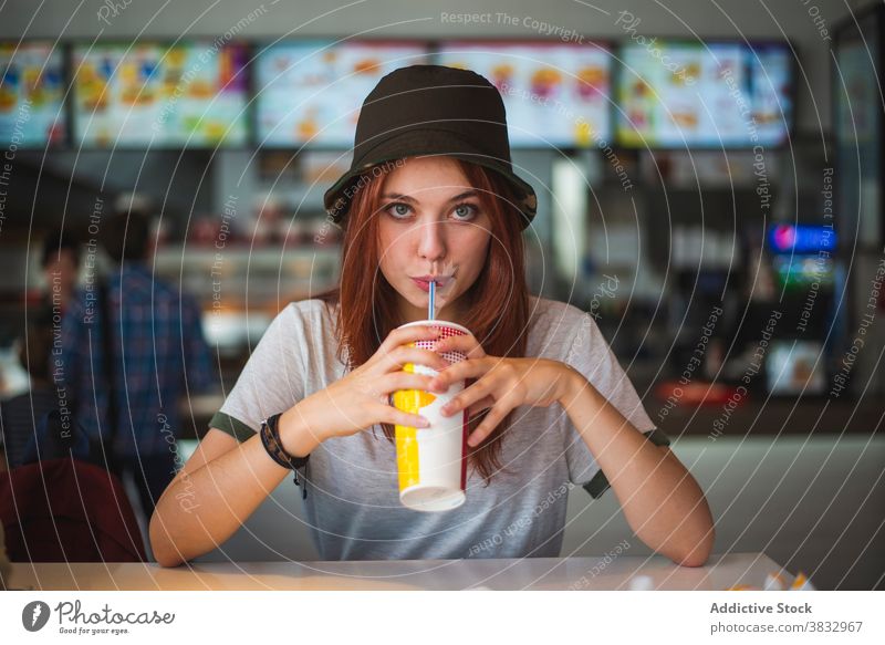 Fröhliche junge Frau, die ein Getränk zum Mitnehmen in einem Café genießt trinken Imbissbude Tasse heiter Hipster Glück Einwegartikel Teenager trendy Kantine