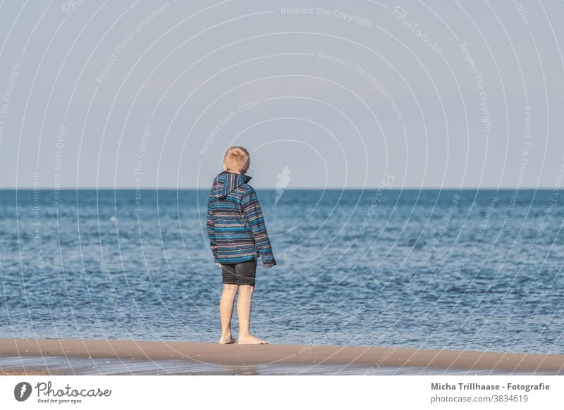 Junge blickt auf das Meer Ostsee Strand Wasser Wellen Kind blond Haare Jacke Jeanshose aufgekrempelt barfuß Sand Blick blicken schauen träumen Horizont Himmel