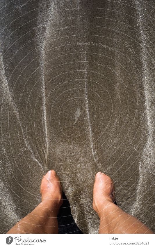 Barfuß lange allein am dunkelbraunen Strand stehen Farbfoto Außenaufnahme Sandstrand Meer Fein Dunkelbraun Wasser Struktur Weich Einsinken Versinken Frauenfüße