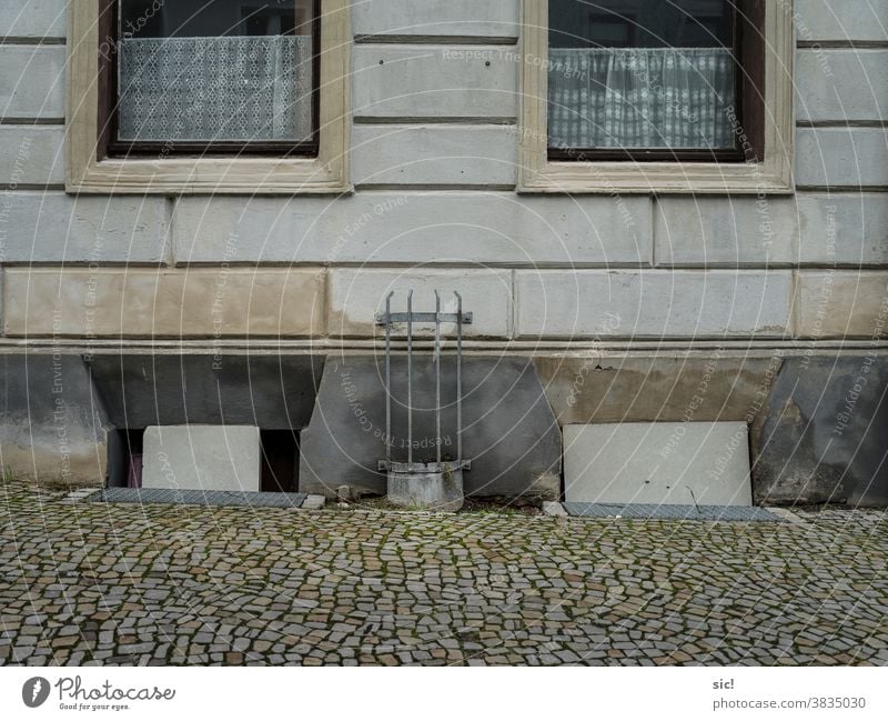 Hauswand mit zwei Blumentöpfen Fenster piefig Fassade Menschenleer Wand Gebäude Außenaufnahme Mauer Farbfoto Architektur trist Gedeckte Farben Kellerfenster