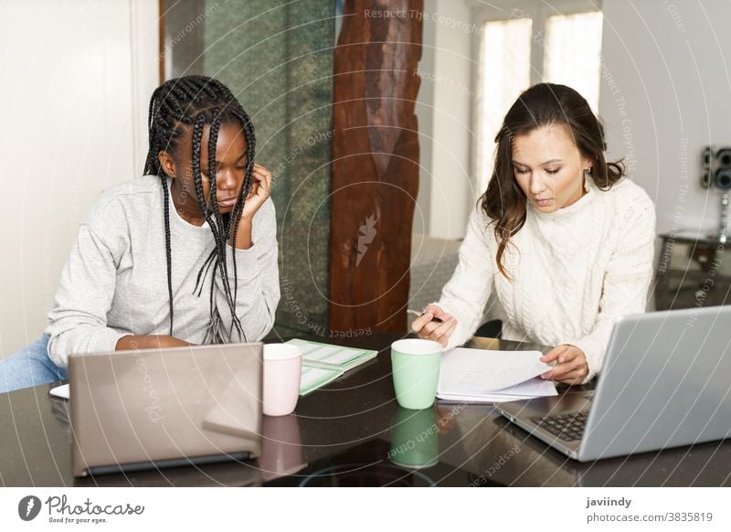 Zwei College-Mädchen studieren gemeinsam zu Hause mit Laptops beim Kaffeetrinken Schüler Frauen multiethnisch heimwärts Computer Hochschule studierend