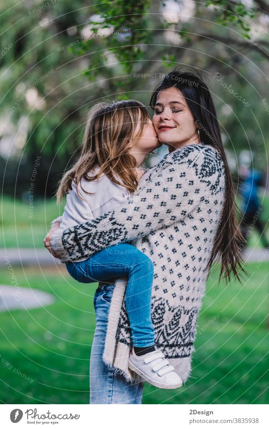 Kleines süßes Kind Baby-Mädchen küsst sich auf die Wange und umarmt, umarmt mit glücklicher hübscher Frau im grünen Park. Mutter, kleines Kind Tochter. Muttertag, Liebe Familie, Elternschaft, Kindheit