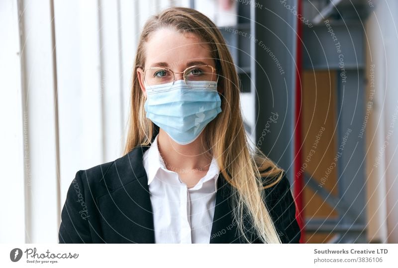 Porträt einer jungen Geschäftsfrau mit Maske, die während einer Gesundheitspandemie in einem modernen Büro steht Business Gesichtsmaske Gesichtsbedeckung