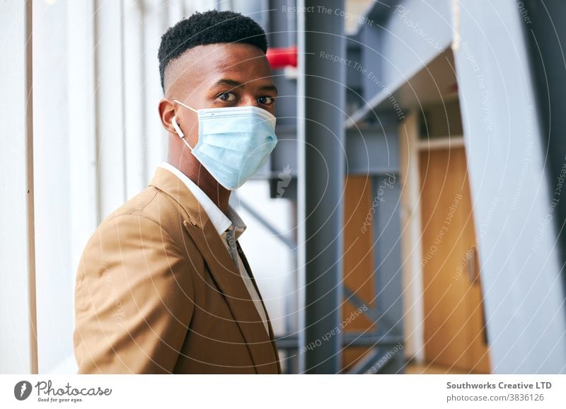 Porträt eines jungen Geschäftsmannes mit Maske, der während einer Gesundheitspandemie in einem modernen Büro steht Business Gesichtsmaske Gesichtsbedeckung