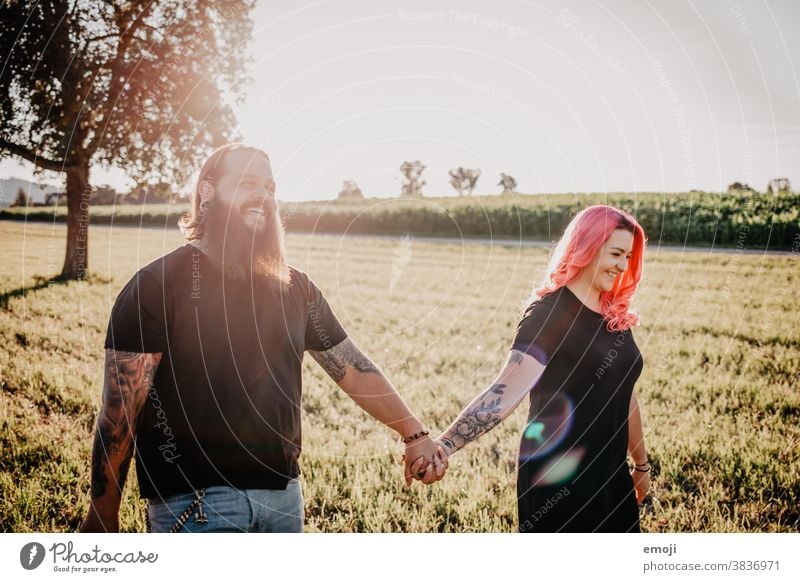 junges Paar mit Tätowierungen und pinken Haaren Hand in Hand jugendlich paar liebe verliebt Draussen feld pinke haare Tattoo trendy Hipster Mann Frau gehen