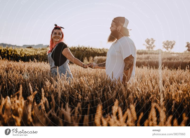 junges Paar mit Tätowierungen und pinken Haaren bei Sonnenuntergang im Feld jugendlich paar liebe verliebt sonnenuntergang Draussen feld pinke haare Tattoo