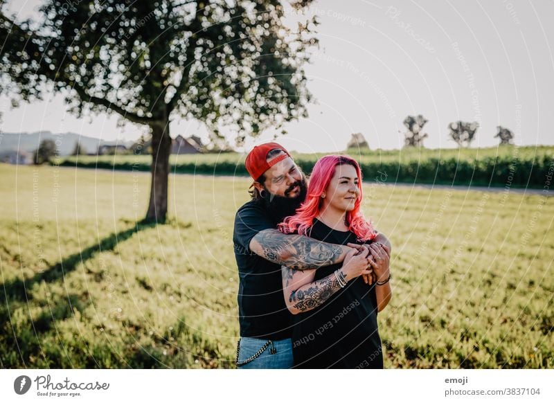 junges Paar mit Tätowierungen und pinken Haaren jugendlich paar liebe verliebt umarmung Draussen feld pinke haare Tattoo innig kuscheln trendy Hipster Mann Frau