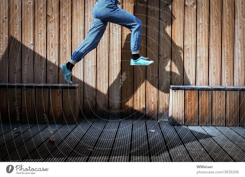 Große Sprünge Sprung springen Holz Bänke Holzbänke Holzwand Turnschuhe Mädchen Kind Schatten Hose munter lustig jung dynamisch Elan Fröhlichkeit Kindheit Spaß