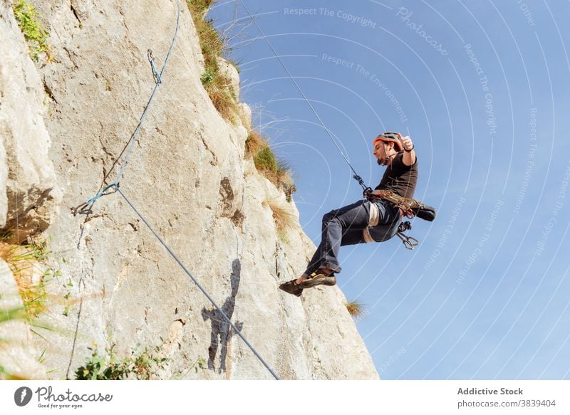 Männlicher Kletterer beim Aufstieg an einer steilen Felswand im Sommer Aufsteiger aufsteigen steile Klippe Mann Alpinist Berge u. Gebirge üben Klettern aktiv