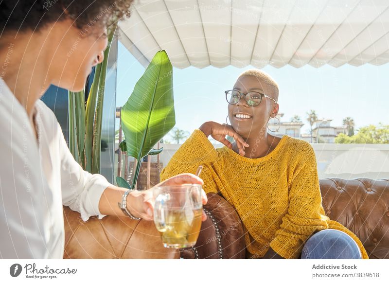 Fröhliche schwarze Frauen erzählen Witze und lachen Freundschaft Spaß haben Lachen bester Freund Humor positiv Terrasse Sommer ethnisch Afroamerikaner reden