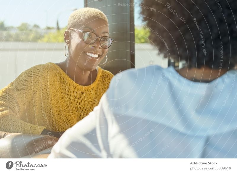 Fröhliche schwarze Frauen erzählen Witze und lachen Freundschaft Spaß haben Lachen bester Freund Humor positiv Terrasse Sommer ethnisch Afroamerikaner reden