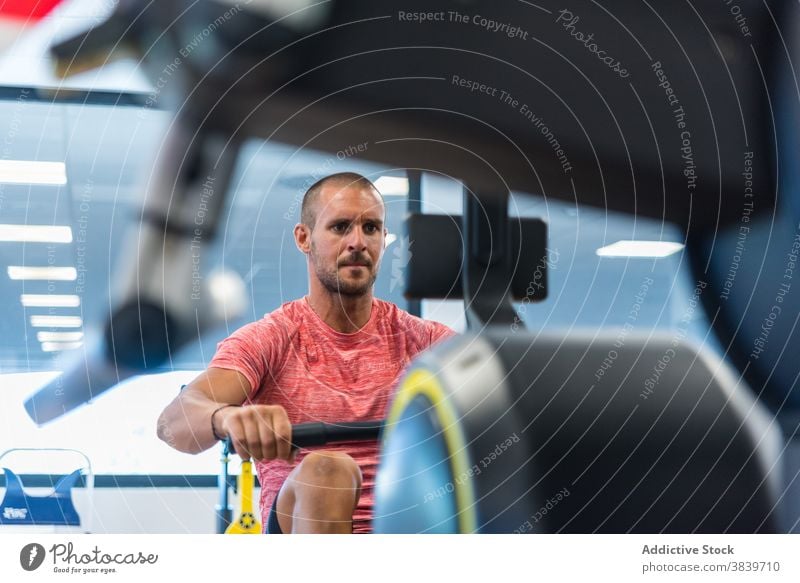 Sportler beim Training an der Rudermaschine im Fitnessstudio Reihe Maschine Übung Mann Trainerin anstrengen männlich Athlet stark Gesundheit Konzentration