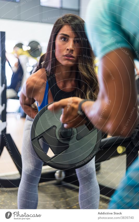 Frau macht Gewichtheben Übungen mit Langhantel unter Aufsicht von Trainer Curl-Hantel Sport Personal Ausbilderin Trainerin deadlift Training ethnisch abstützen