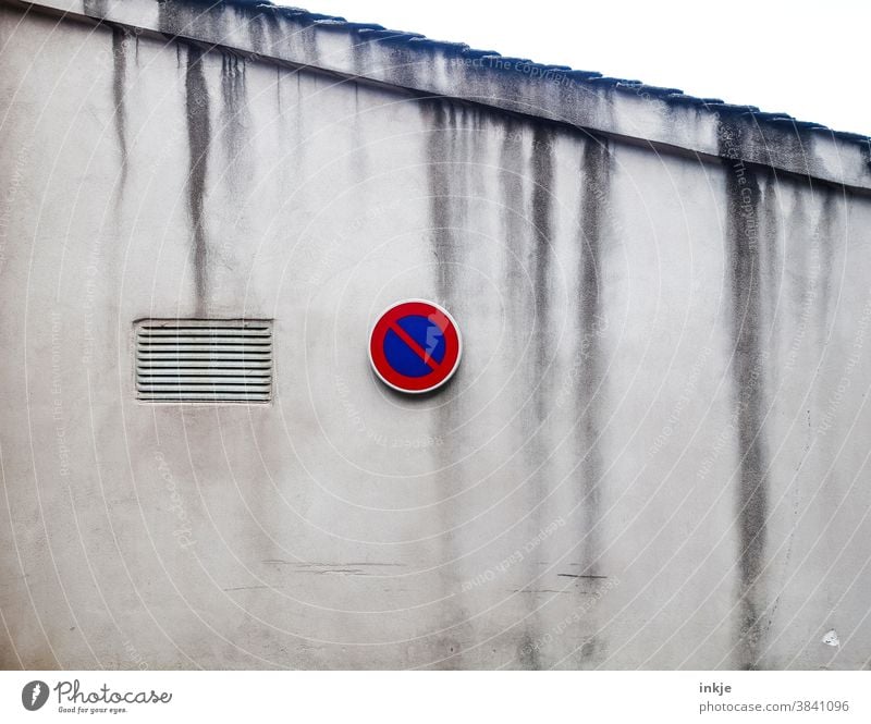 Halteverbotsschild an Fassade mit verlaufenen Schmutzstreifen Farbfoto Außenaufnahme Menschenleer Straßenschild Verbot Schmutzig Trist grau Streifen Dachziegel