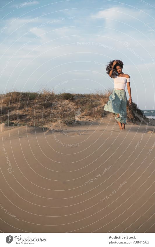 Serene Frau zu Fuß auf Sandstrand bei Sonnenuntergang sorgenfrei Sommer Spaziergang Strand Barfuß Anmut ruhig Outfit Hügel Natur charmant genießen Freiheit jung