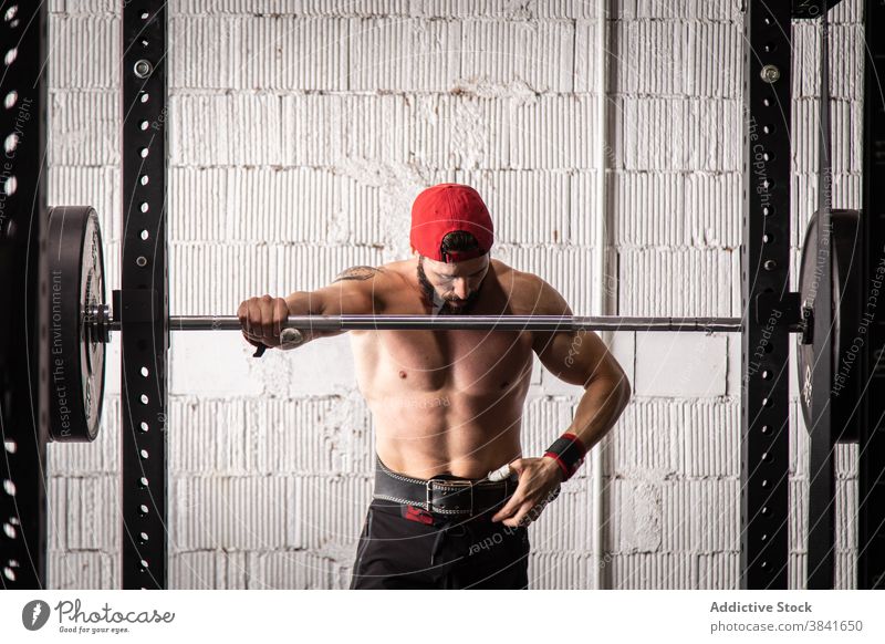 Muskulöser Sportler im Gewichthebergürtel im Fitnessstudio Gewichtheben Training Mann Gurt Gerät professionell muskulös stark männlich nackter Torso ohne Hemd